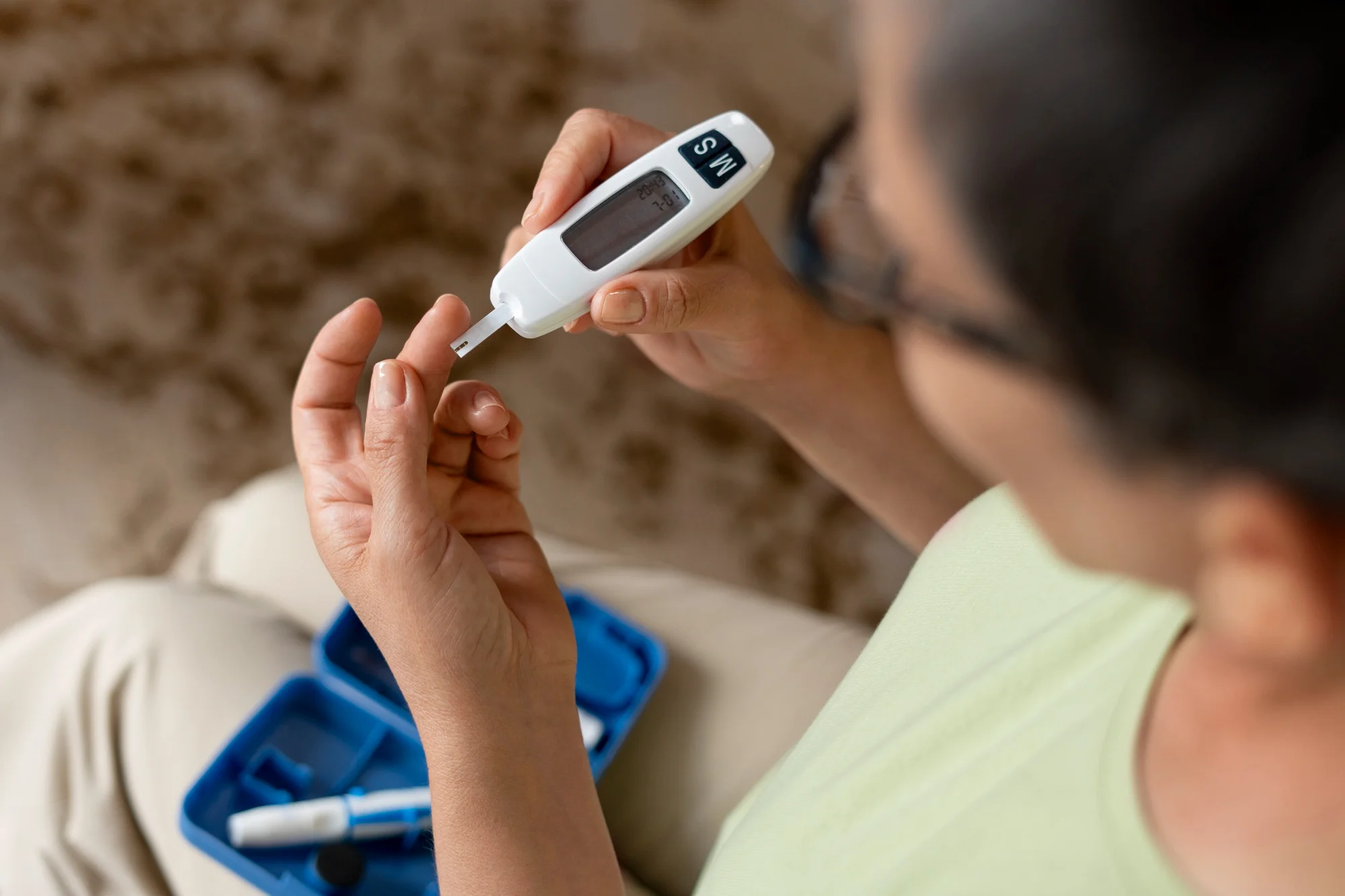 A person checks their blood sugar level using a glucometer, showing a routine finger-prick test commonly used to monitor glucose levels in daily diabetes care.