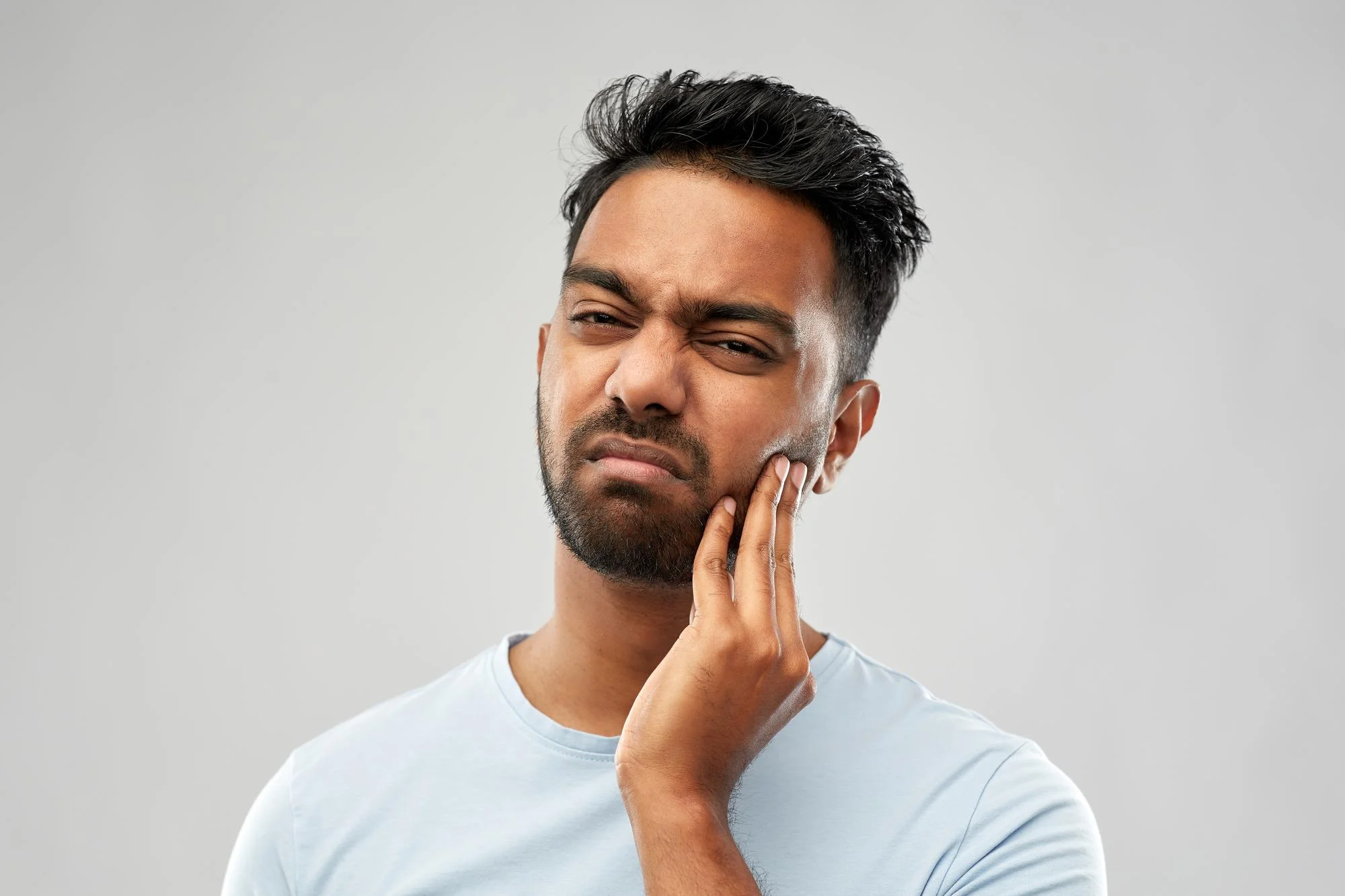 This image shows a man holding his jaw due to facial tension and jaw pain, which are common symptoms treated with Masseter Botox. Masseter Botox helps relax overactive jaw muscles, reducing pain, clenching, and discomfort caused by TMJ and bruxism.