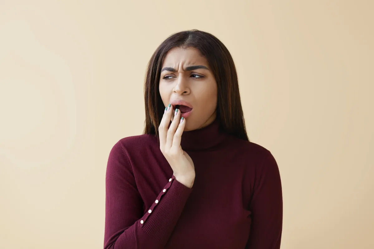 Close-up of a woman touching her lips while looking uncomfortable, representing mild tongue burn pain