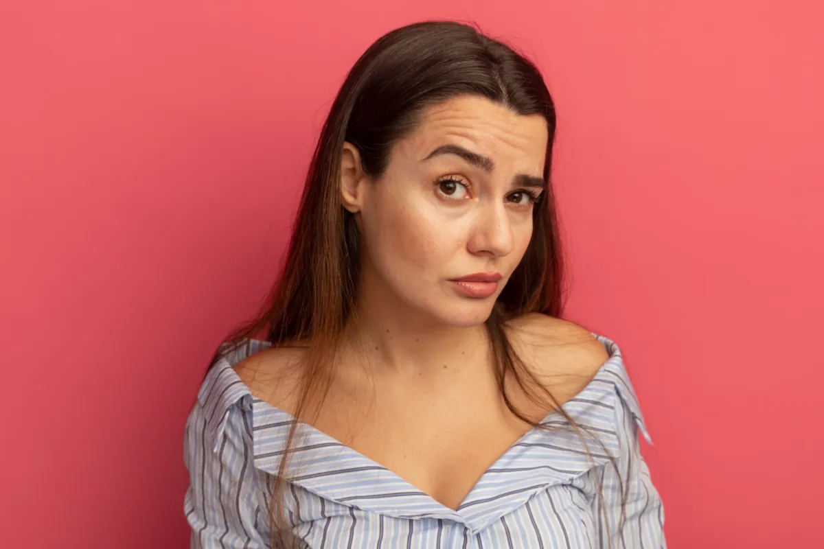 Young woman raising her eyebrows with visible fine lines on the forehead, demonstrating early signs of forehead wrinkles.