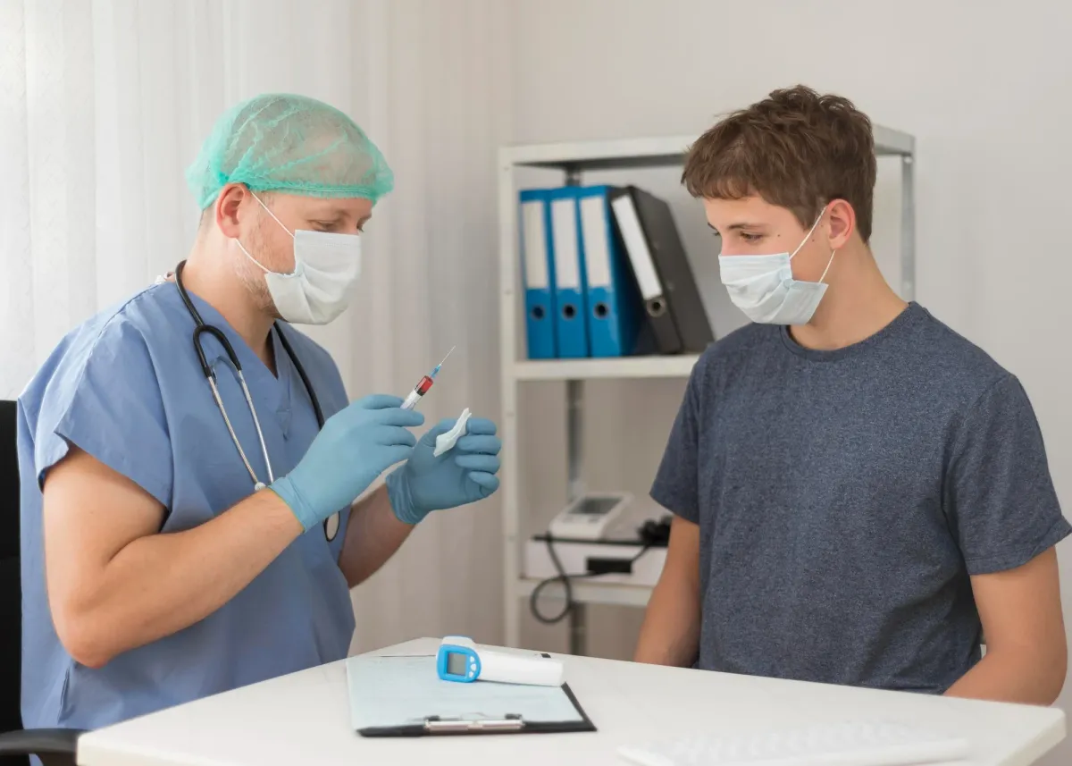 Healthcare worker preparing a syringe for a TB skin test while a masked teenage patient looks on in a clinic room.