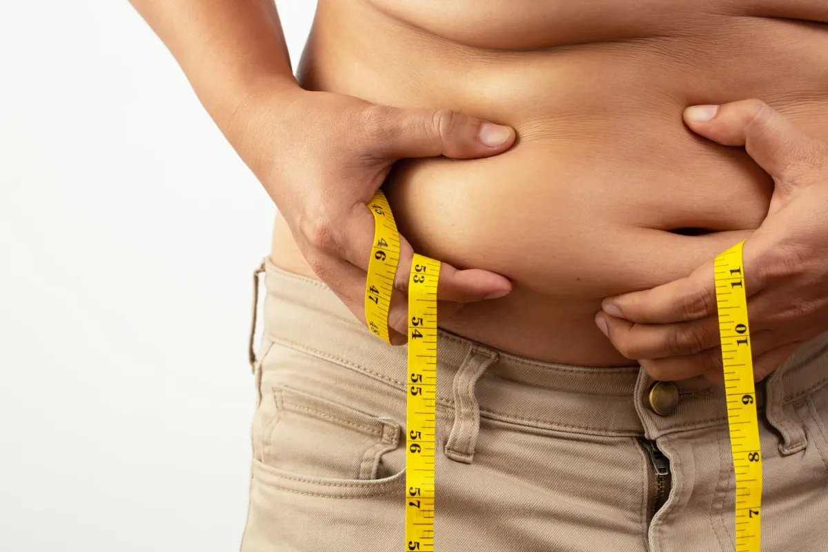 person holding and measuring excess abdominal skin and fat, often referred to as an apron belly