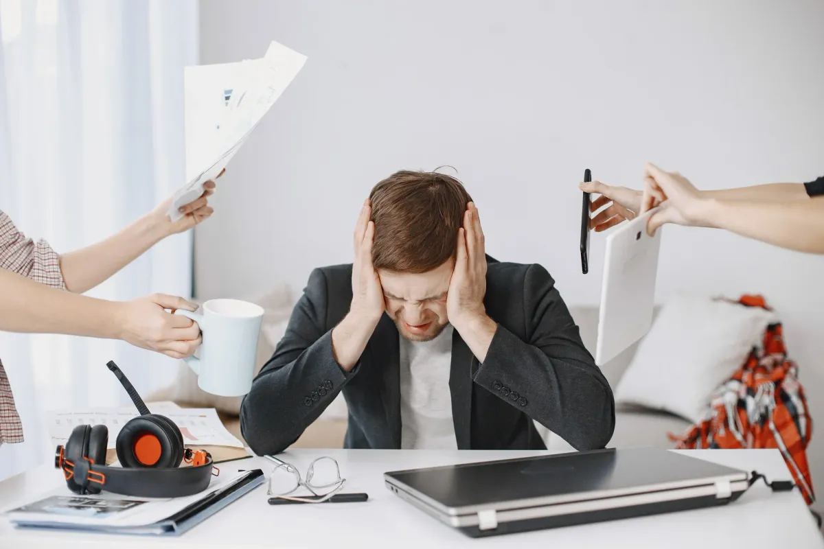 feeling stressed at desk with multiple distractions, representing stress management challenges with Holisticke approach.