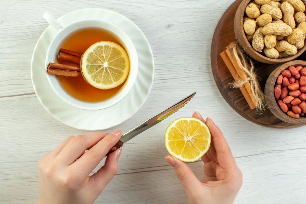 Homemade lemon tea in a white cup with cinnamon sticks and fresh lemon slices, showcasing the Best Tea for Sore Throat.