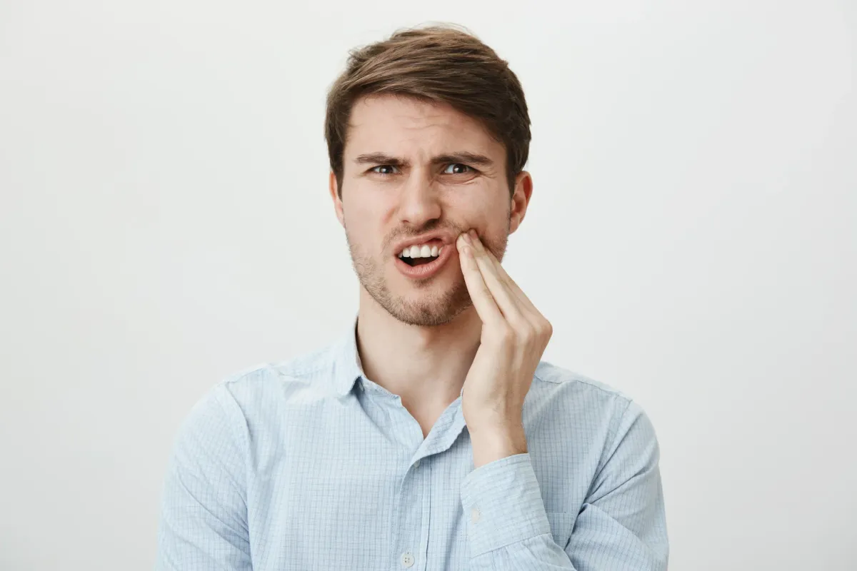 um Disease vs Gum Recession featured image showing a person experiencing dental discomfort.