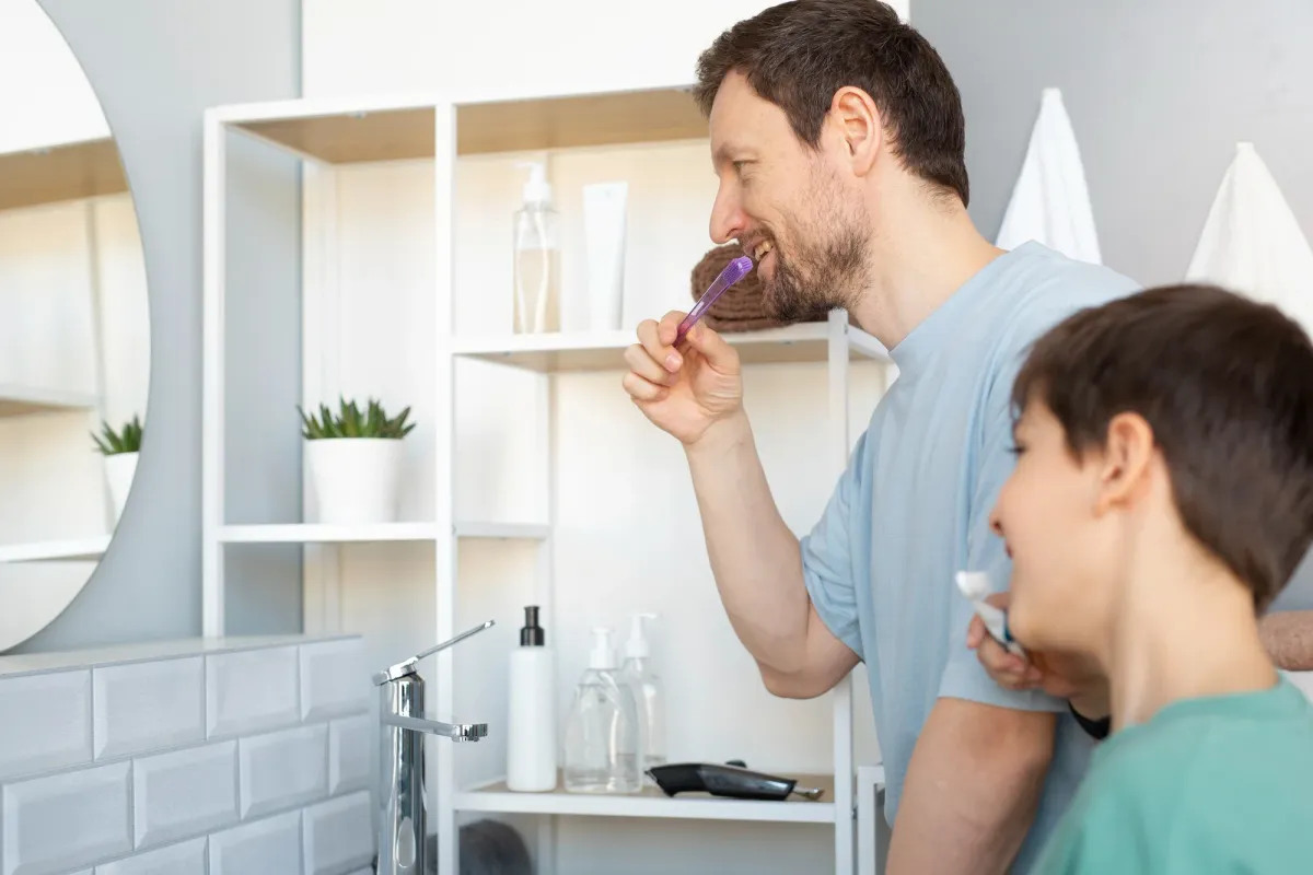 Parent and child brushing their teeth together in a bathroom, illustrating the importance of daily oral hygiene in the debate between Water Flossers vs Traditional Floss.