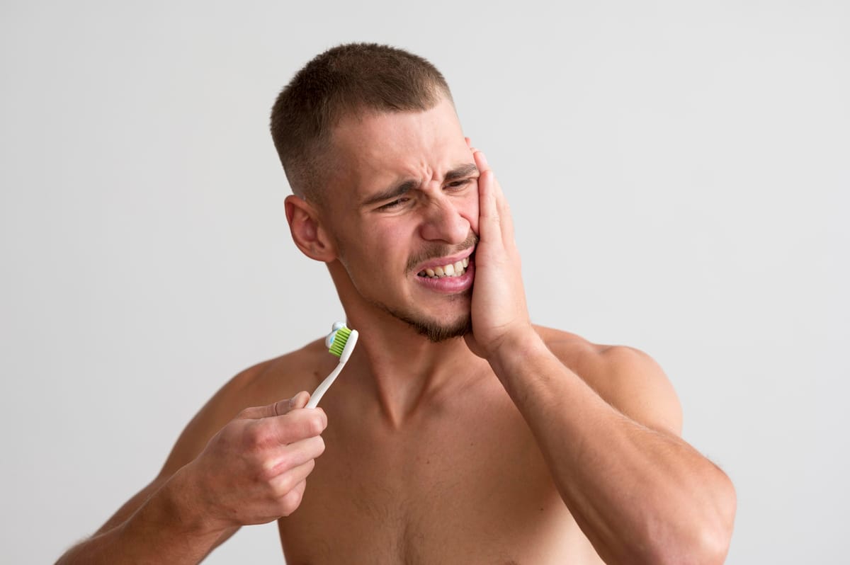 Person experiencing dental pain while brushing teeth, highlighting symptoms of tooth decay, gum disease, or sensitive teeth.